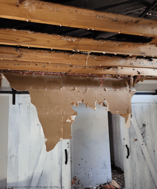 Open ceiling with exposed framing and damaged wall finishes in a fire-damaged interior