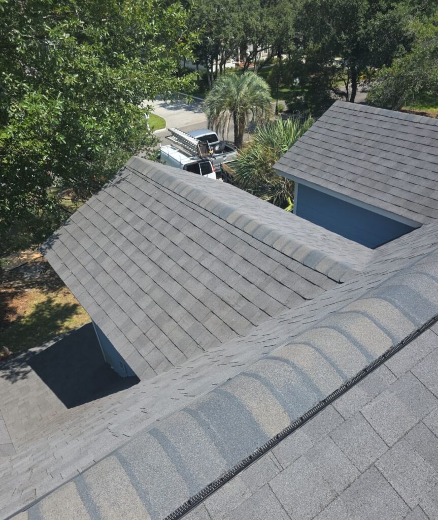 Gray architectural shingles and capped ridges over the blue Caswell Beach home
