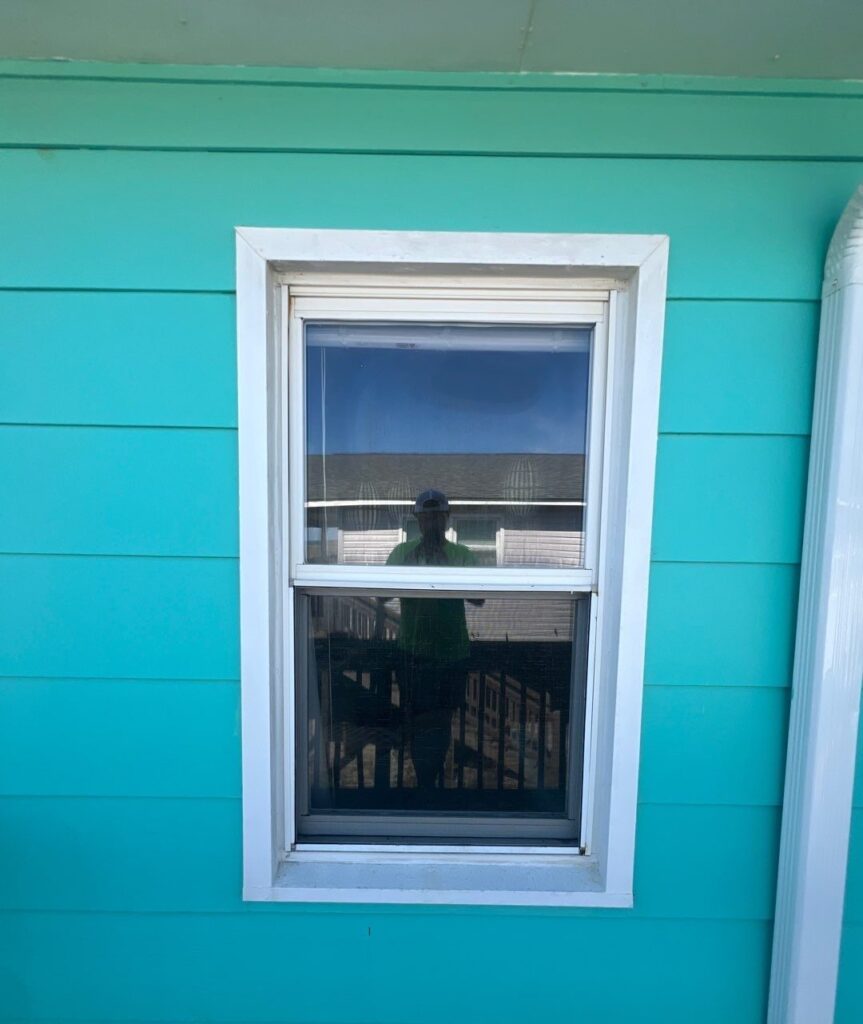 White single-hung window set into turquoise siding in Oak Island, NC
