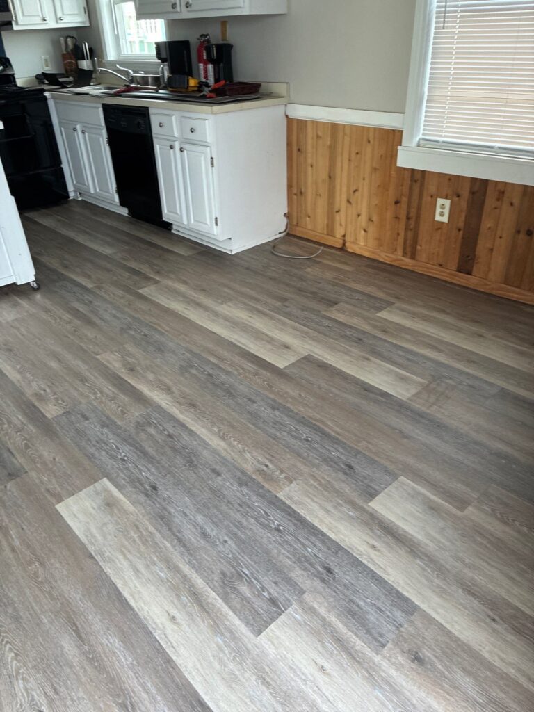Plank flooring beside the kitchen cabinets and wood paneling in Oak Island, NC
