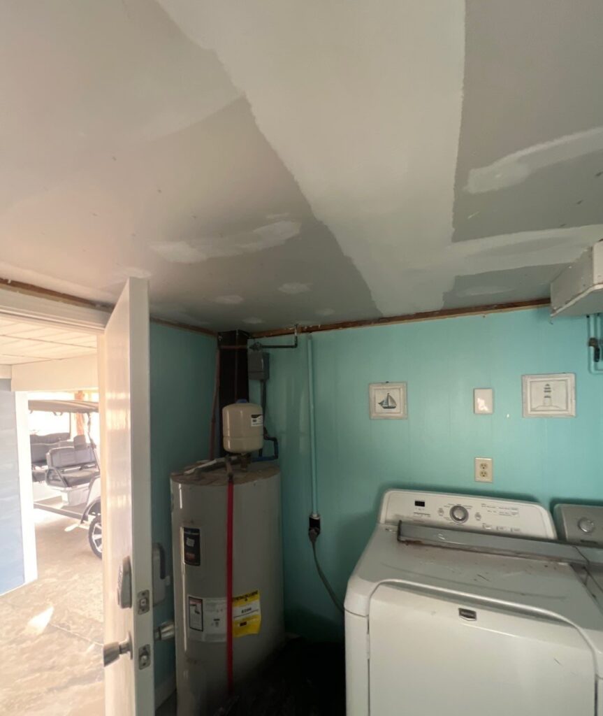 Patched ceiling above the laundry appliances and turquoise walls in Oak Island, NC