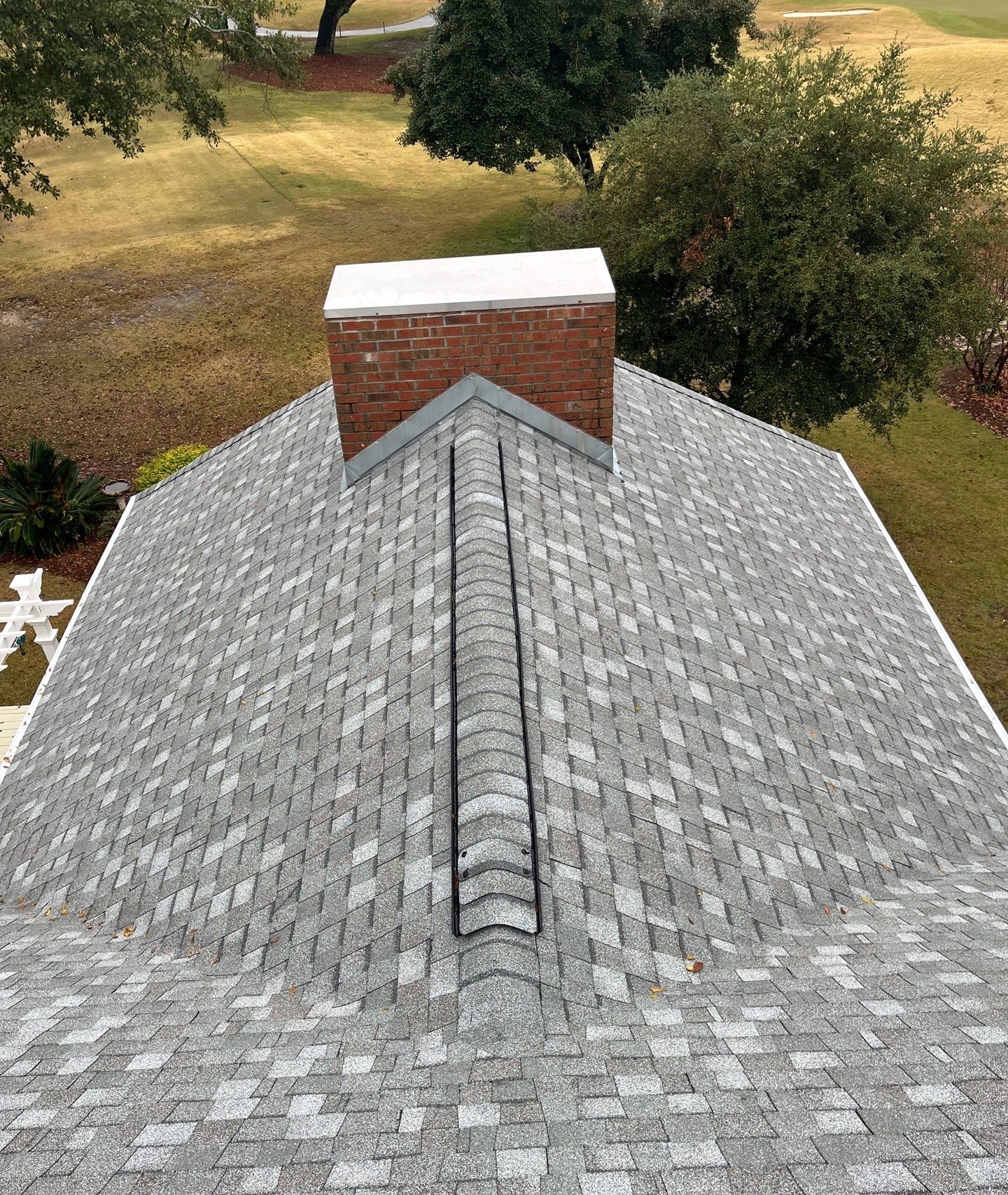 Roof ridge and shingle planes beside the brick chimney in Oak Island, NC