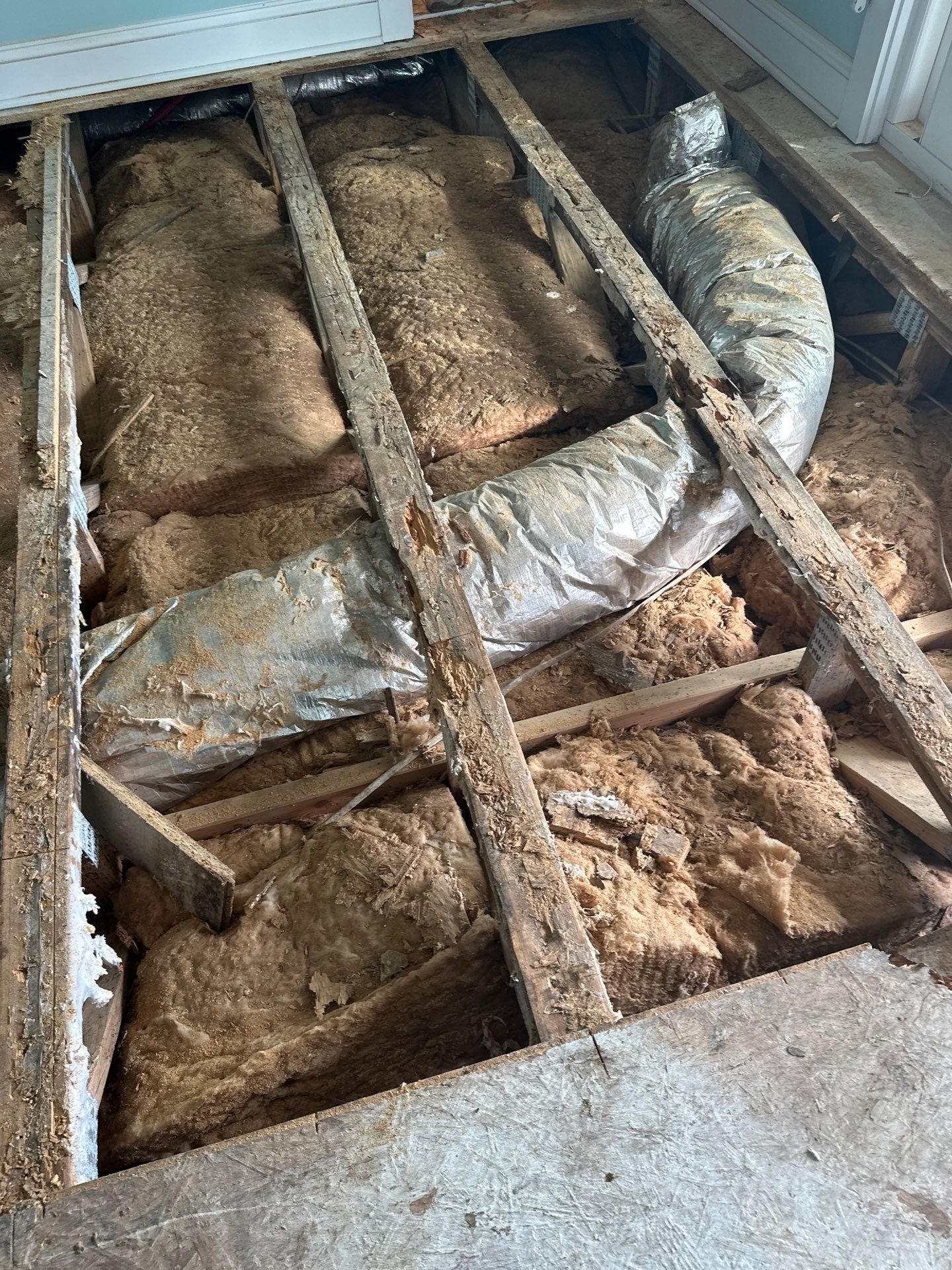 Opened floor exposing damaged framing and insulated ductwork in Oak Island, NC