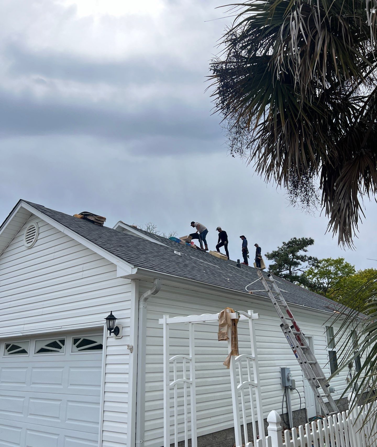 Roofing crew working above the side elevation in Oak Island, NC