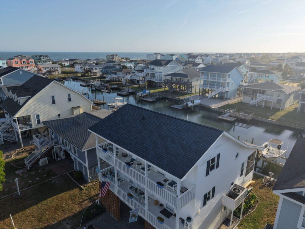 Aerial view of the completed Coastal Blue shingle roof on a white canal-side home in Holden Beach